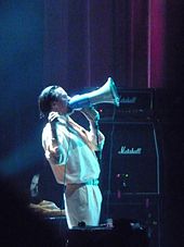 A man dressed in white singing through a megaphone