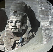 View of the rightmost statue at the Great Temple, partially excavated, with a human figure (possibly William Henry Goodyear) for scale