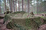 Camouflage netting is draped away from a military vehicle to reduce its shadow.
