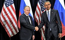 Obama shakes hands with Vladimir Putin in front of Russian and American flags.