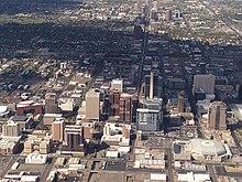 photo taken from an aircraft showing the tall buildings of downtown Phoenix, with the mountains which surround the city in the background.