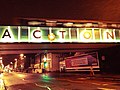 Nighttime view of Acton sign on the railway bridge at the bottom of Acton High Street in London.