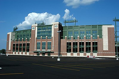 A photo of the facade of Lambeau Field, with the parking lot in the foreground