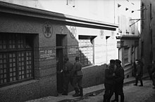 Photograph of a synagogue used as a brothel. Three German soldiers can been seen entering it.