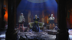 Multiple clones of a woman, each wearing a differing outfit, in a deserted house.